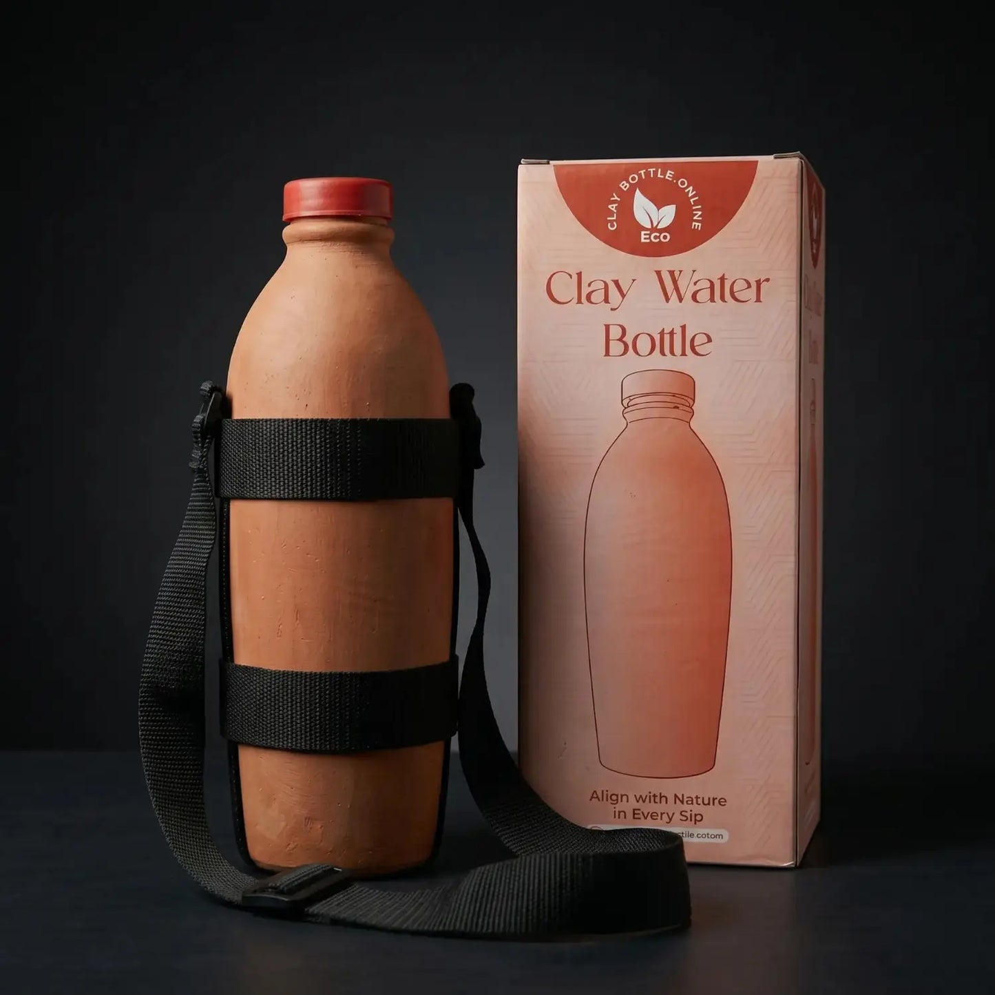 An authentic unpainted mitti ki bottle with a black shoulder strap standing next to its custom eco-friendly product box labeled Clay Bottle Online.